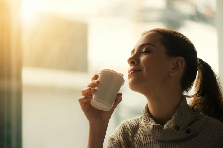 Woman enjoying a quiet morning with coffee by a sunlit window